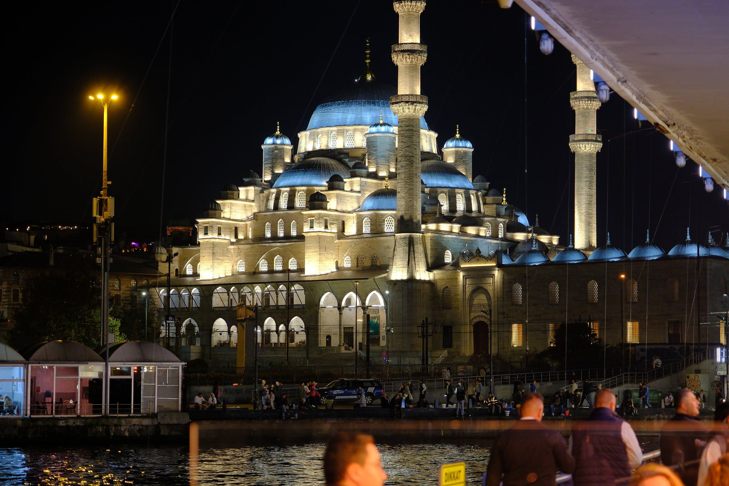 Gece ışıklandırılmış Yeni Cami, restoranın köprü altındaki masalarından