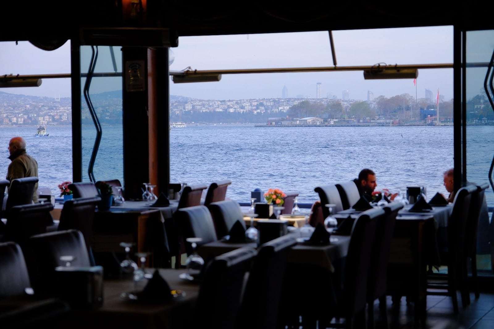 Window tables at dusk looking out over the Bosphorus from under the Galata Bridge